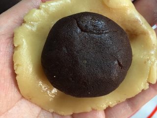 6、红豆蛋黄陷月饼,把月饼皮团子压扁中间薄边区厚，中间放入做好的红豆蛋黄陷，然后封口