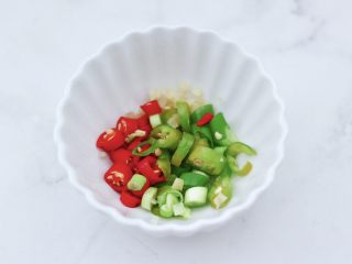 3、白灼鲍鱼,把切好的小米辣和绿尖椒，姜末和小葱放入碗里。
