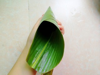 9、杂豆蜜枣小米粽,然后手捏住上面那一头粽叶转一圈，形成更长的牛角形状，看不懂的多看上图和此图的区别，就明白了