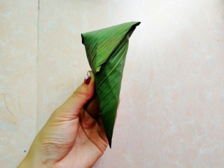 13、杂豆蜜枣小米粽,再把顶端的往下折，如图，然后用粽绳绑起来