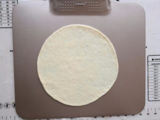 6、培根薯角薄底披萨,把醒发好的面团擀成薄薄的面饼，放到烤盘上。