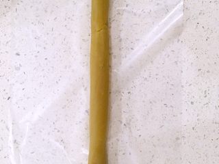 6、一口莲蓉酥,铺上保鲜袋，取100克的莲蓉馅在保鲜袋上搓成30厘米左右长的长条。
