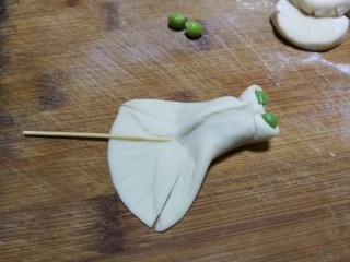 8、金鱼饺子,前段中间往里面收，捏成两个小孔当作金鱼眼睛，分别在小孔里面放两粒小豌豆，尾巴处先用牙签压出花纹印记，然后在尾巴处对称切两刀，分割出鱼鳍部分