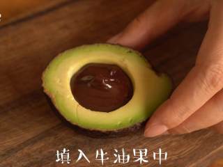 2、感受水果原香【牛油果冰淇淋】,取出果核；使用巧克力融锅将黑巧克力融化，填入果核凹槽里面，冷藏30分钟至巧克力凝固变硬。