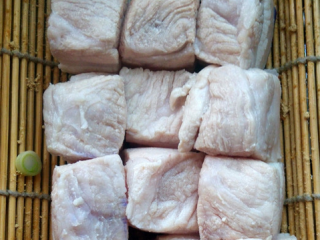 5、家常东坡肉,大砂锅里用竹箅子垫底，先铺上葱和姜，再将猪五花的皮面朝下，排在上面