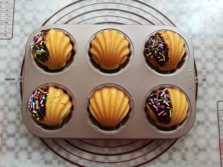 17、炫彩柠檬玛德琳,在玛德琳蛋糕上刷上适量的巧克力酱,沾上适量的彩色糖针