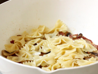 11、培根蛋黄奶油意面,蘑菇炒出水后，把蝴蝶意面放入锅中翻炒一二分钟，期间调入盐和黑胡椒粉炒匀。因为培根有足够的咸度，所以调味时盐根据口味少量加。