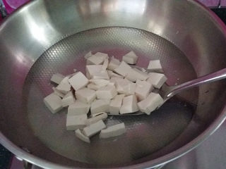 4、#了不起的小番茄# 蟹黄豆腐烩番茄,锅中加少许食盐，放入豆腐块煮开捞出、去除豆腥味