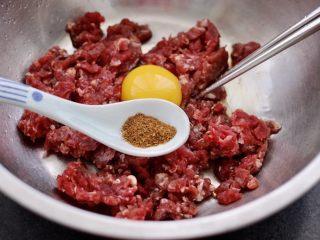 2、蒜黄牛肉饺子,把牛肉馅放入一个大一点的容器里，打入1枚鸡蛋，倒入花椒粉。
