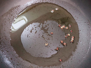 9、葱爆鱿鱼,锅中倒入油,加热至五成热,煸香花椒粒。