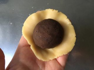 8、广式蛋黄豆沙月饼,取一块面团在手掌上按成圆形后放入蛋黄豆沙馅，用虎口慢慢收紧封口后搓圆