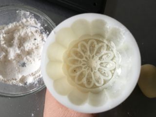 10、广式蛋黄豆沙月饼,月饼模具里撒上面粉晃荡均匀后倒出多余的粉