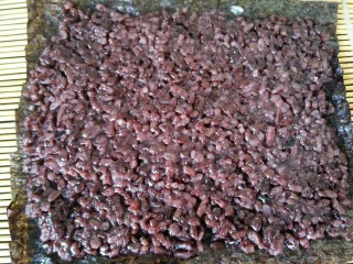 3、黑米寿司,然后用铲子均匀的铺在海苔上