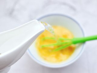 5、飞蛤豆腐鸡蛋羹,再分次加入温水，（鸡蛋液的1倍温水最合适）搅拌均匀。