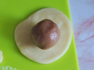 11、香芋蛋黄酥,将面团擀开，放入馅，用虎口包起。