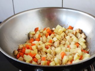 9、咖喱土豆胡萝卜鸡丁饭,放入胡萝卜丁和土豆丁，翻炒均匀。