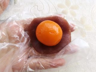 7、广式蛋黄月饼,把馅料按扁包好蛋黄。