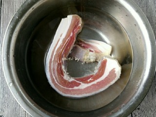 2、香煎腊肉,腊肉洗掉表面的盐粒,再用刀口刮洗肉皮部分;彻底洗净后,用清水浸泡片刻,去除多余的盐分;