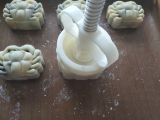 23、广式月饼~网红大螃蟹咸蛋黄月饼,把月饼模具直接倒扣在烤盘里，轻轻压几下，用力要均匀，然后压片压下去同时用手指把月饼模具抬起，压片完全推出；