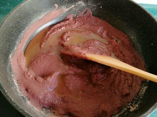 6、自制红豆沙馅,把中火调到小火,加入二分之一的玉米油,加了玉米油的豆沙变的比之前稀了一些。