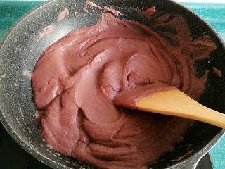 7、自制红豆沙馅,把火调回中火,然后不停地搅拌,直到玉米油和豆沙完全融合在一起。