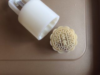 14、蛋黄豆沙月饼,在烤盘上压出月饼，在表面喷一层清水。（离月饼有一定的高度，不是直接喷在月饼上）