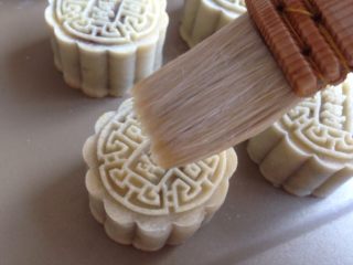 16、蛋黄豆沙月饼,在表面刷一层薄薄的蛋黄水，侧面不用刷。不能刷太多，可以用毛刷沾蛋黄液，在碗口刮去多余的蛋液再刷