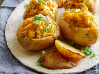 3、奶酪烤土豆,碗里的土豆泥中加入2汤匙黄油,RICOS浓缩车打芝士酱和酸奶油,放入葱段,辣酱,辣酱,盐和胡椒粉,搅拌均匀。