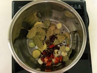 11、红烧羊肉,炖锅烧热后加入1小勺大豆色拉油,油烧热后加入姜片和葱段,香叶和花椒粒炒出香味