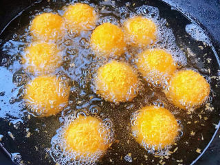 10、油炸汤圆,锅中倒入适量油加热至五成热放入黑芝麻汤圆中火炸起来