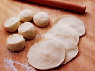 11、果仁红糖发面饼,把剂子摁扁后,用擀面杖擀成圆形薄面皮。