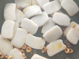 16、年年高升广式腊肠炒年糕,倒入沥干水的年糕。