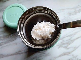 8、#简约营养的#紫薯粥,5分钟后将焖烧罐的水倒掉，加入提前泡好的大米。