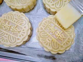 15、广式月饼,再用毛刷把蛋液均匀的刷在月饼上,刷蛋液的时候动作要轻,每刷一次之前,要把毛刷在碗边刮一下,以防多余的蛋液刷在月饼上面会积成一坨,那样会影响美观不好看。