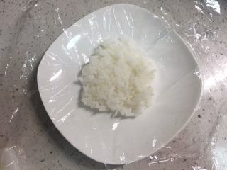 2、火腿芝士雪娃娃饭团#诞愿有你#,取45左右的克米饭，放在保鲜膜中间。