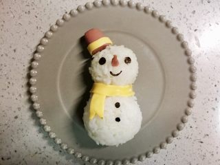 12、火腿芝士雪娃娃饭团#诞愿有你#,用海苔剪出眼睛鼻子和扣子，用一点火腿，切成尖尖的鼻子，安在饭团上。完成～