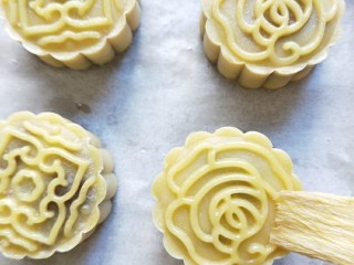 23、广式蛋黄豆沙月饼,月饼表面喷微量水，放入预热好的烤箱200度烤5分钟定型，再取出刷上一层薄薄的蛋黄水