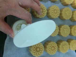 16、#甜味#莲蓉蛋黄月饼,放入烤盘中,一手按住下面模具不可移动,另一手向下按压,力道不要太重,也不要太轻,压花月饼就好了