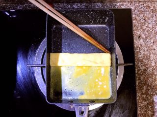 6、日式厚蛋烧,待蛋液底层成型，但表面还未完全熟的时候用筷子小心的从上往下开始内卷。里层未完全熟的蛋液能把蛋饼牢牢粘住，不会松散，后面的操作会把蛋液全部煎熟的，不用担心