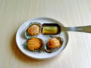 8、蒜蓉粉丝蒸鲍鱼,把小鲍鱼放壳里,加入料酒,每个鲍鱼肉上淋一点。