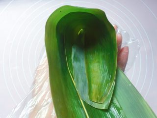 6、蜜枣西米粽子,在粽叶的1/3处折起，折出一个漏斗形状（漏斗下方一定要紧密，不然会漏米）；