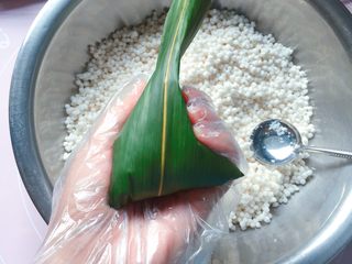 10、蜜枣西米粽子,再把粽叶上端的叶子向下折，直到完全盖住开口的地方就好了；