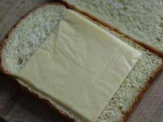 6、乳酪榴莲土司披萨,将奶酪片平铺在土司上