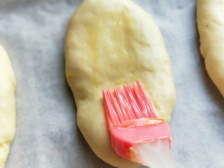 17、香葱培根芝士面包,发酵好的长舌状面胚刷上一层蛋液。