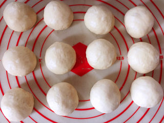 6、日式红豆包,发酵好的面团按压排气，平均分成12个面团，将它们都滚圆之后盖上保鲜膜松弛15分钟。