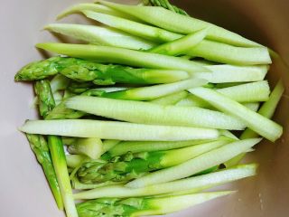 3、迷迭香黑胡椒牛排,将芦笋斜刀切成小段放入碗中备用。