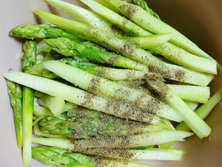 4、迷迭香黑胡椒牛排,在芦笋上撒上一些盐、黑胡椒粉。