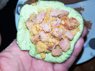 5、菠菜青团,取一块面团，在掌心按扁，包入肉松香肠馅儿。