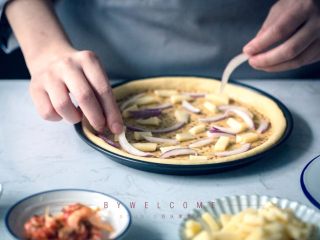 12、麻辣小龙虾披萨,在扎了洞的面饼上刷上少许小龙虾汤汁，放上三分之一的马苏里拉碎，再放上10g洋葱；