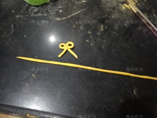 15、花样馒头——粽子馒头,之前预留的5克白色面团加入少许南瓜粉。揉成黄色面团，然后搓一个细长条，再做一个蝴蝶结。